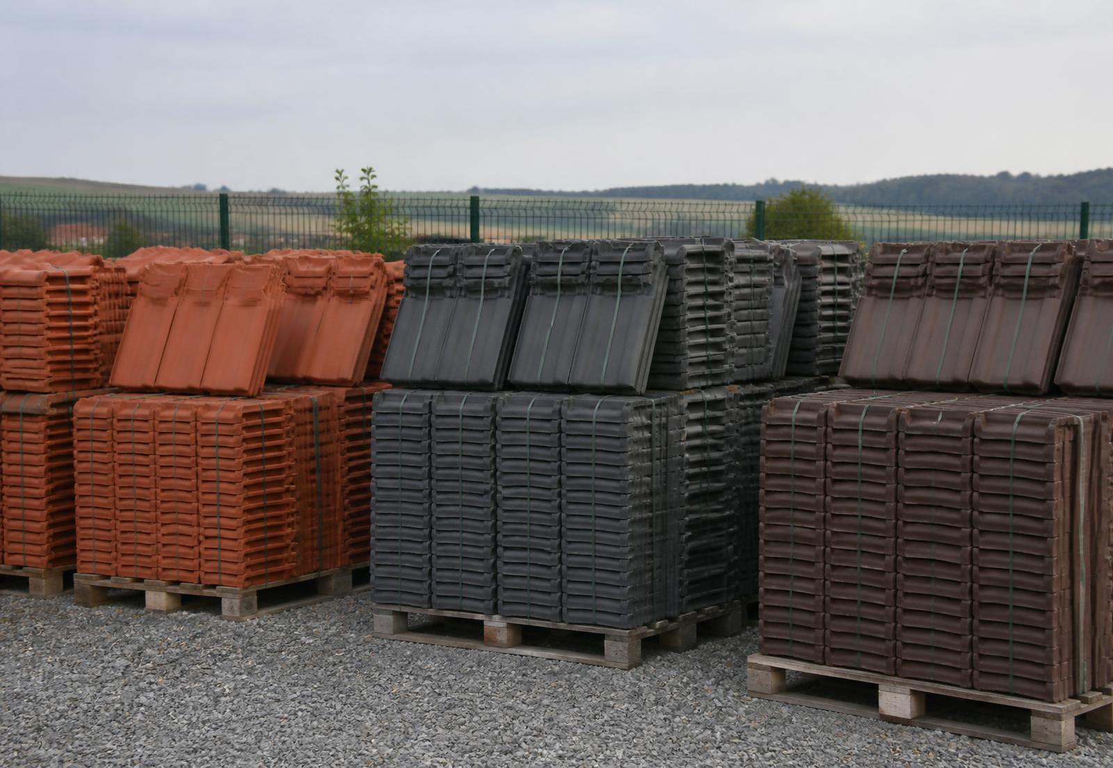 Palety betonových a pálených střešních tašek na skladové ploše prodejny ve Starovičkách